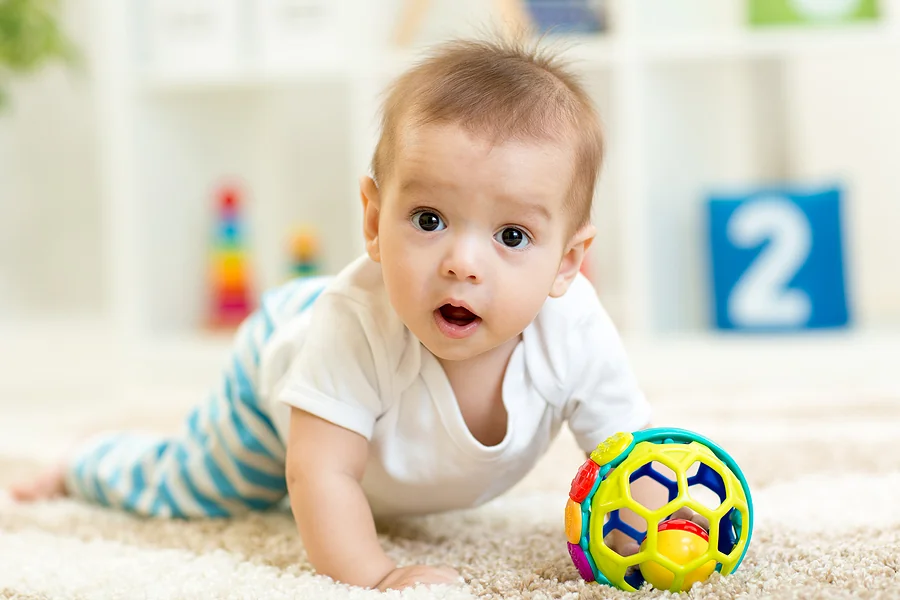 Baby crawling on the floor in nursery room