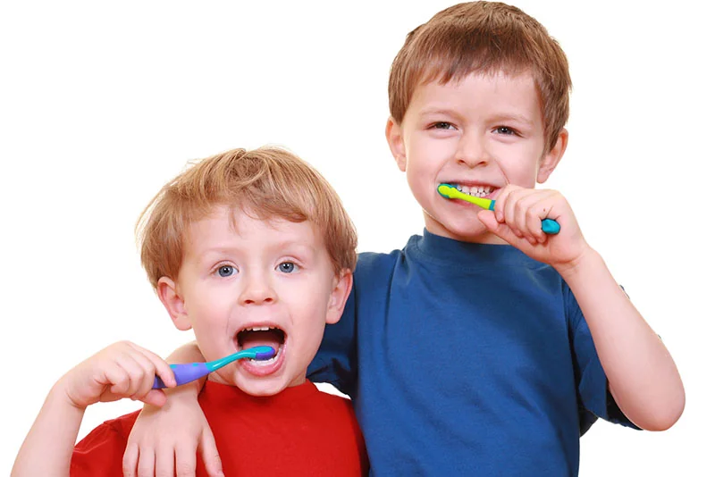 Two boys brushing their teeth at the dentist